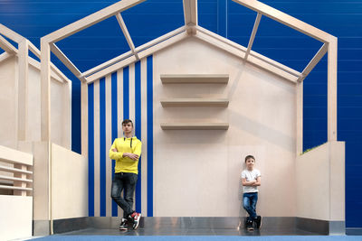 Young father and son stand under the roof of wooden frame house. two brothers or friends