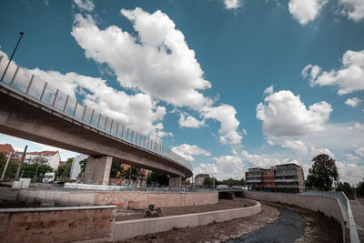 View of bridge and buildings against cloudy sky