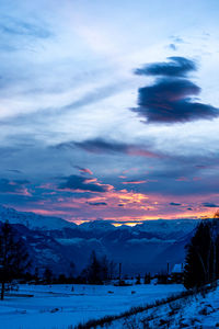 Scenic view of snowcapped field against sky during sunset