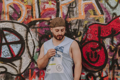 Full length of young man standing against graffiti wall