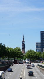 Cars on road by buildings against sky