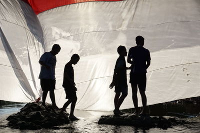 Silhouette people standing in sea