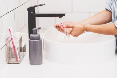 Midsection of woman cleaning hands at sink