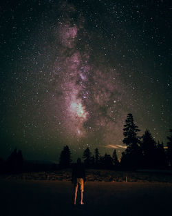 Man standing on road against star field at night