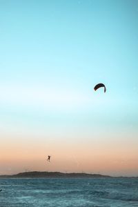 Person paragliding in sea against sky