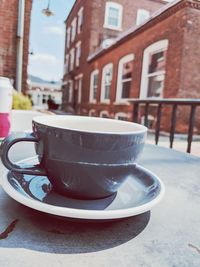 Close-up of coffee cup on table against building