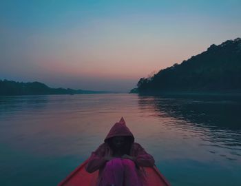 Low section of man against lake during sunset