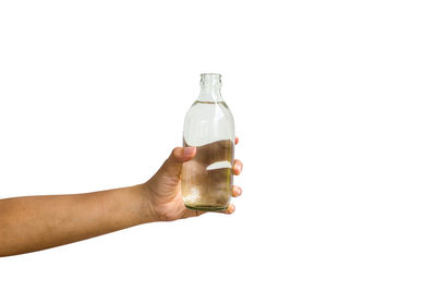 Midsection of person holding glass bottle against white background