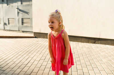 Portrait of young woman standing on footpath