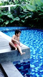 Side view of a boy sitting on poolside