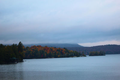 Scenic view of lake by trees against sky