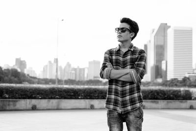 Young man wearing sunglasses standing against city