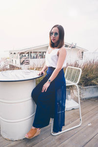 Portrait of young woman sitting at table against clear sky