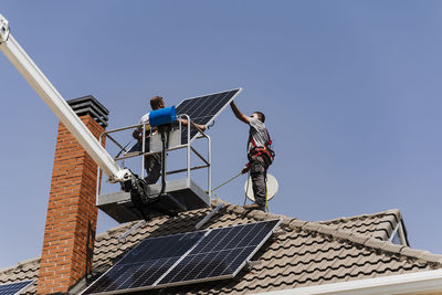 Technicians unloading solar panel from hydraulic platform