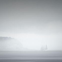 Boat sailing in sea against sky during foggy weather