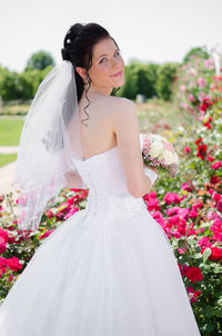 Portrait of bride standing by roses at park