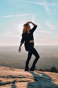 Full length of woman posing while standing on mountain against sky 