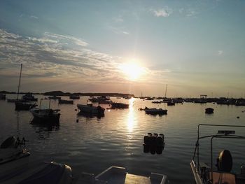 Sailboats moored on sea against sky during sunset