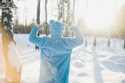 Rear view of mid adult man standing on snow covered field in forest