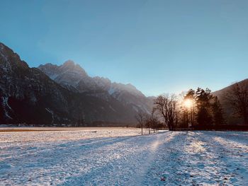 Snow covered land and mountains against clear sky