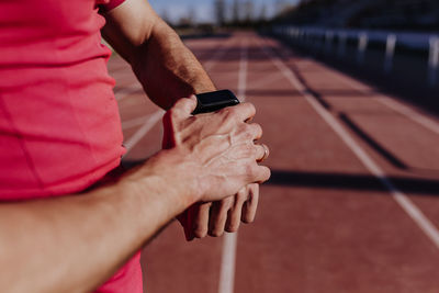 Midsection of athlete wearing smart watch on sports track