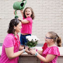 Happy siblings standing against pink wall