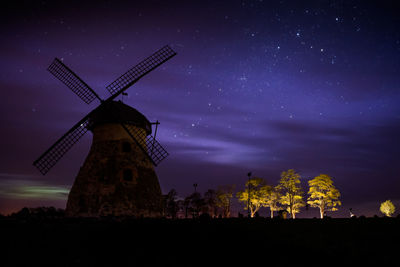 Traditional windmill on field against sky at night