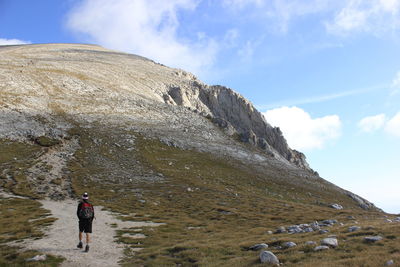 Low angle view of man walking on mountain against sky