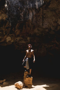 Man looking up while standing on rocks in cave