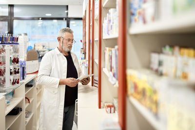 Pharmacist holding tablet pc working in pharmacy store