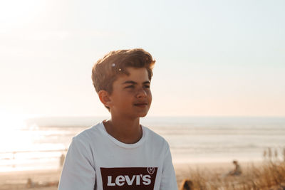 Portrait of boy standing at beach against sky