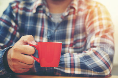 Midsection of man holding coffee cup