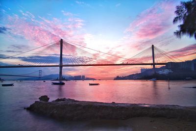 Suspension bridge over river during sunset