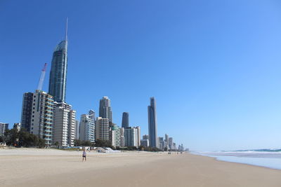 Modern buildings by sea against clear sky