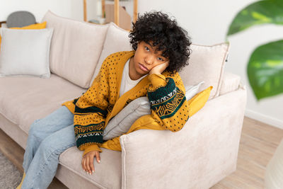 Portrait of young woman sitting on sofa at home