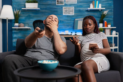 Midsection of man using mobile phone while sitting on sofa