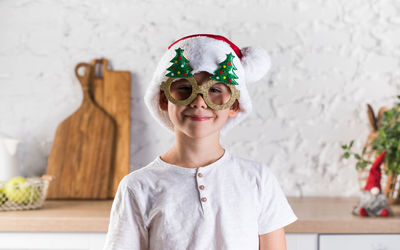 Portrait of young woman wearing sunglasses while standing against wall