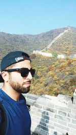 Portrait of young man wearing sunglasses against mountain