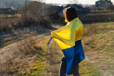 Woman holding a yellow and blue flag of ukraine in outdoors