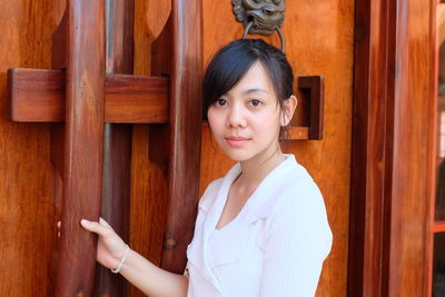 Portrait of young woman standing by door