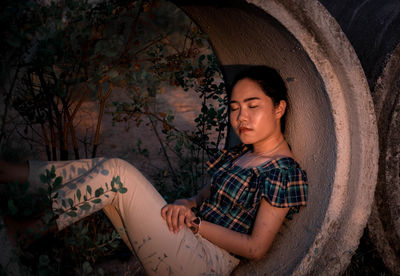 Young man sitting in concrete pipe