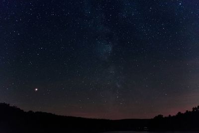 Low angle view of silhouette landscape against star field at night