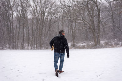 Rear view of man walking on snow covered landscape