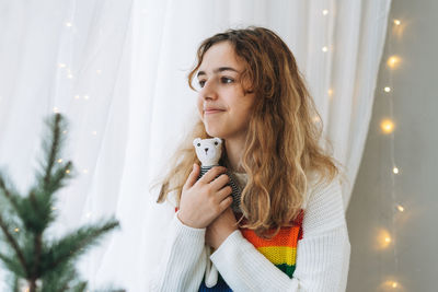 Beautiful teenager girl with bear toy sitting on windowsill in cozy children room