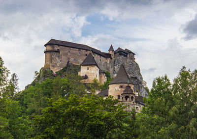 Low angle view of historic castle and trees against cloudy sky