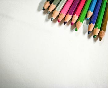 High angle view of multi colored pencils against white background