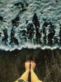 Low section of woman standing at beach