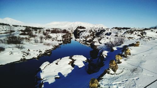 Scenic view of lake by snowcapped mountains against sky