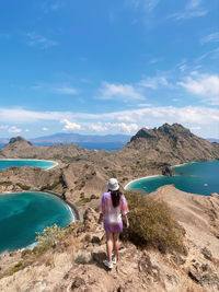 Rear view of woman standing on mountain against sky