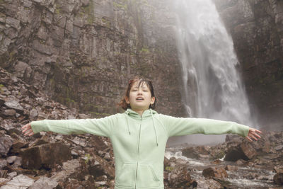 Girl standing in front of waterfall